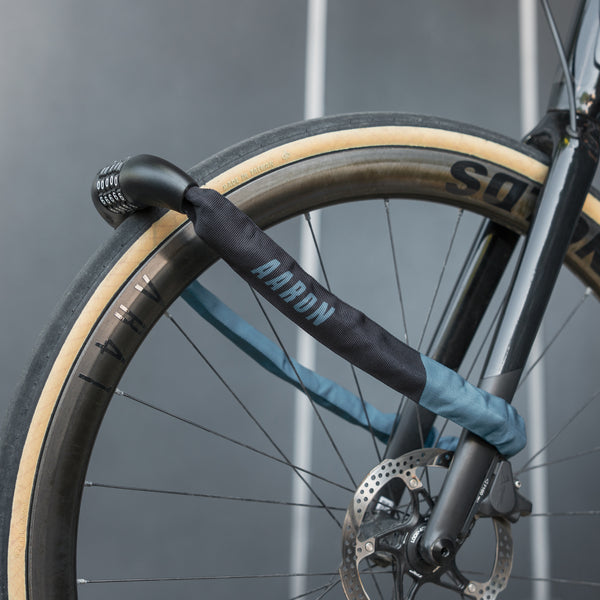 AARON Lock One Fahrradschloss mit Zahlencode - Grau Blau II an Fahrradreifen und Gabel montiert vor grauem Hintergrund