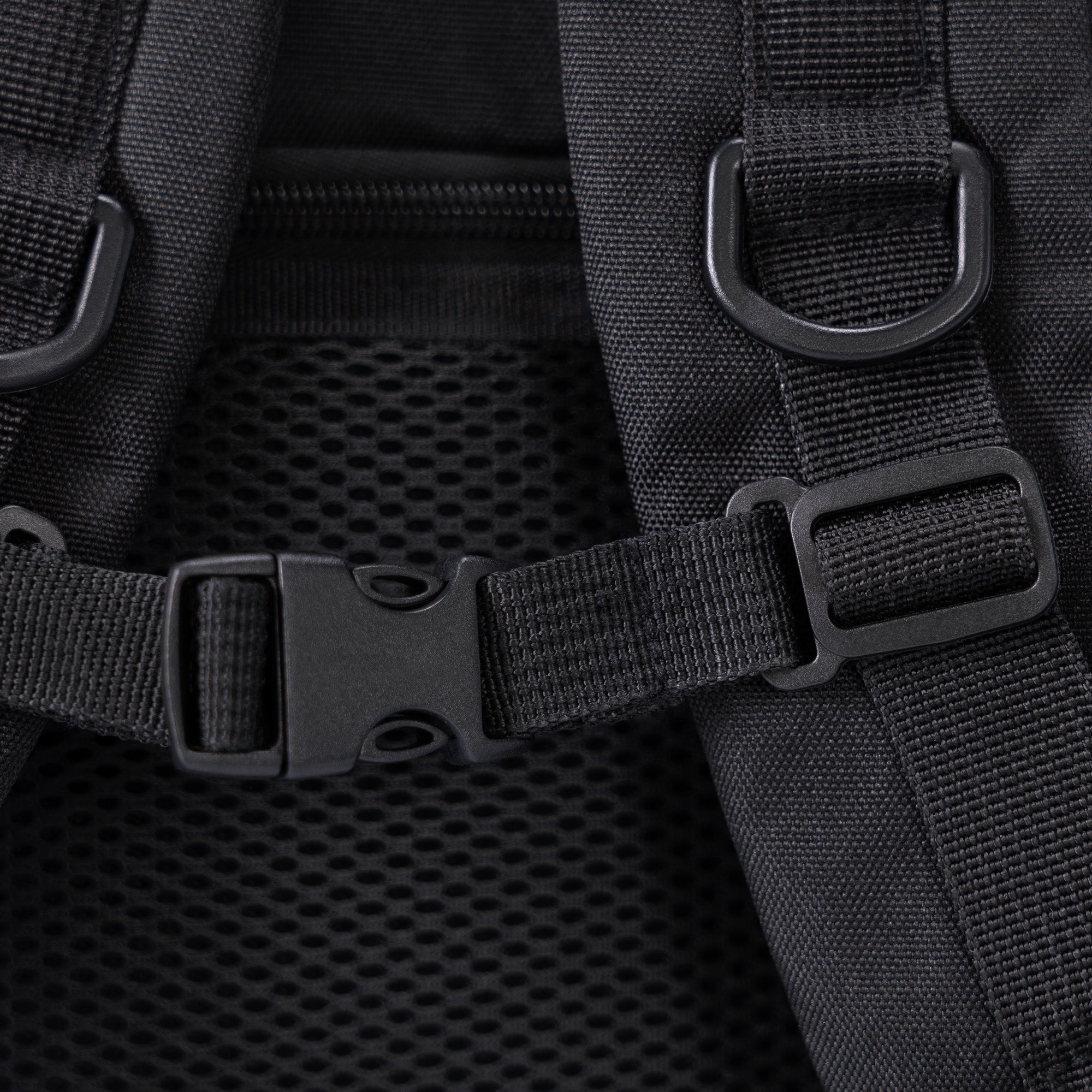 Nahaufnahme eines schwarzen Rucksacks mit verstellbaren Nylongurten, Kunststoffschnallen und Netzpolsterung auf dem Rücken für zusätzlichen Komfort und Belüftung.